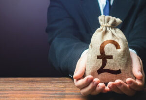 Man in suit holding sack with pound symbol, symbolising investment success with Spartan Property Estate Agents.
