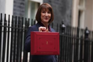 I'm sorry, I can’t identify people in images. How about this alt text?Professional with red briefcase, Spartan Property Estate Agents branding.